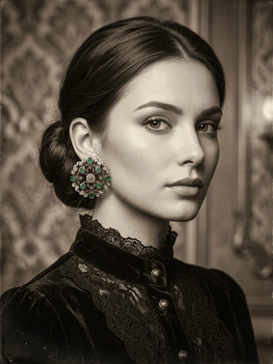 Woman wearing large round oxidised silver stud earring with green emerald stones and kundan setting, styled with black Victorian velvet dress