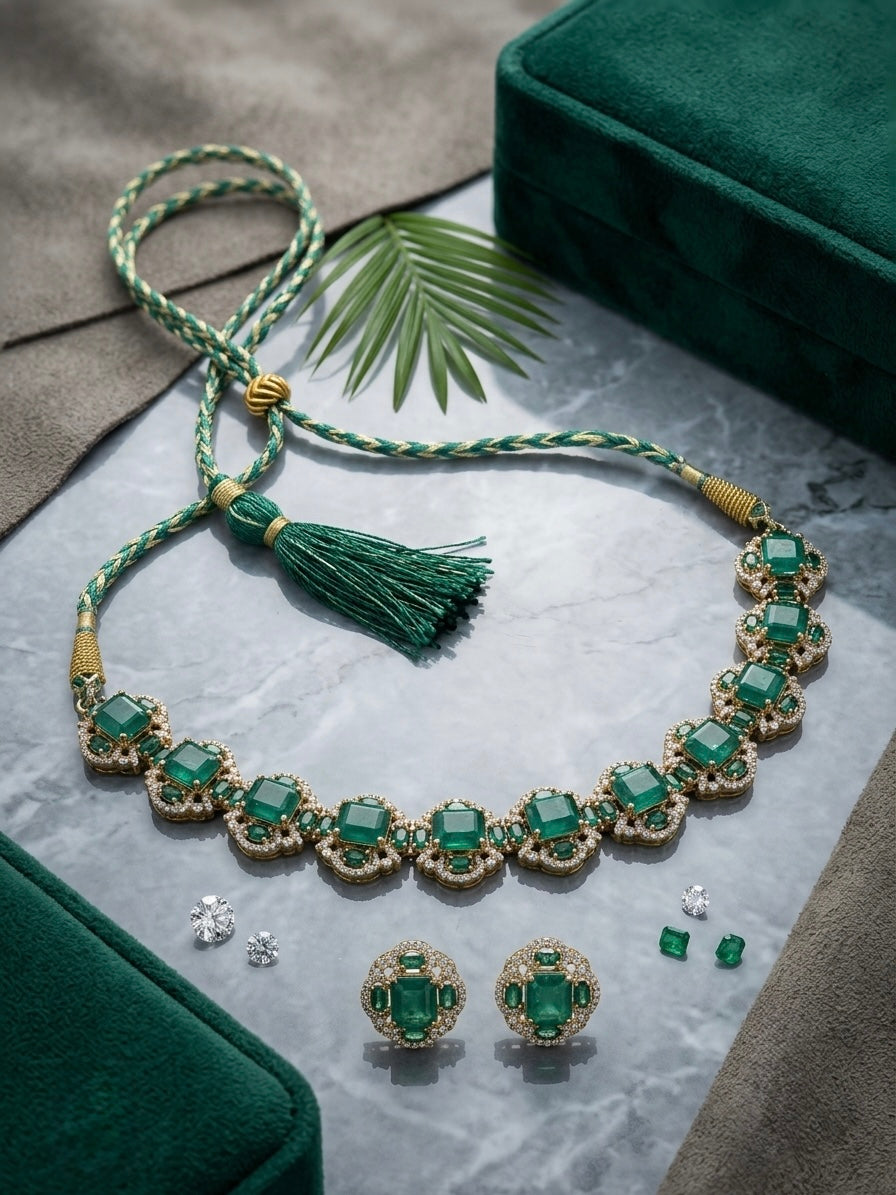 Artificial green onyx Victorian-style choker necklace and stud earrings set with gold-tone kundan setting, braided silk dori tassel closure, displayed on marble with loose diamonds and emerald stones