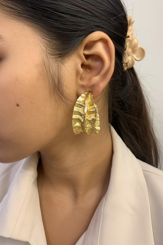 Textured Wave Gold Hoop Earrings in brass gold plating displayed on a white marble surface, featuring a ruffled wave-like surface design with stud backs.